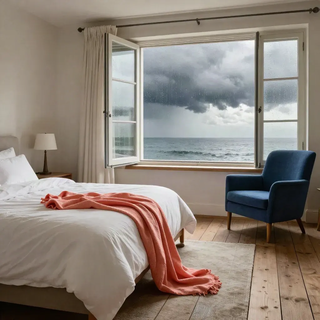 Coral-throw sea-view suite with blue armchair, storm light, and bright bay horizon.